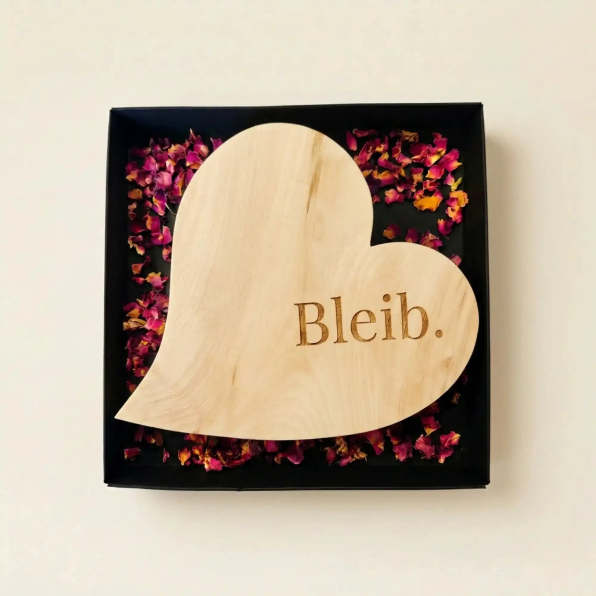 Hochwertige Geschenkverpackung fuer das Zirbenherz Bleib – schwarze Box trifft auf goldene Satinschleife. Hochwertige Geschenkverpackung fuer das Zirbenherz Bleib – schwarze Box trifft auf goldene Satinschleife.