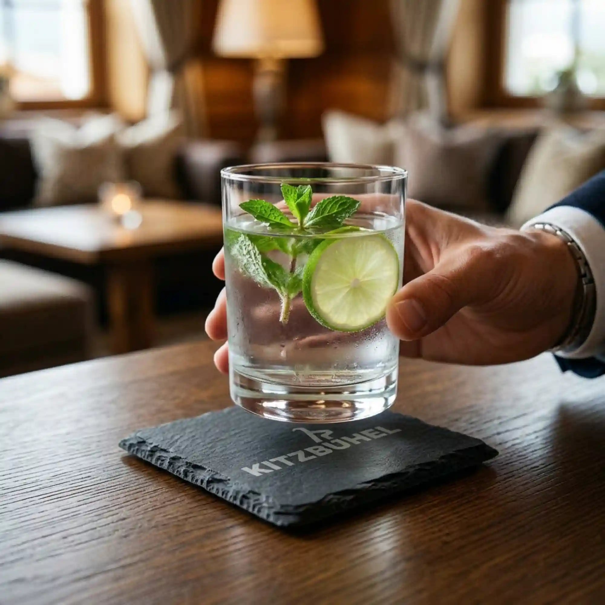 Schiefer Untersetzer mit lizenzierter Kitzbuehel Gravur auf rustikalem Holztisch in einer Hotelbar. Schiefer Untersetzer mit lizenzierter Kitzbuehel Gravur auf rustikalem Holztisch in einer Hotelbar.