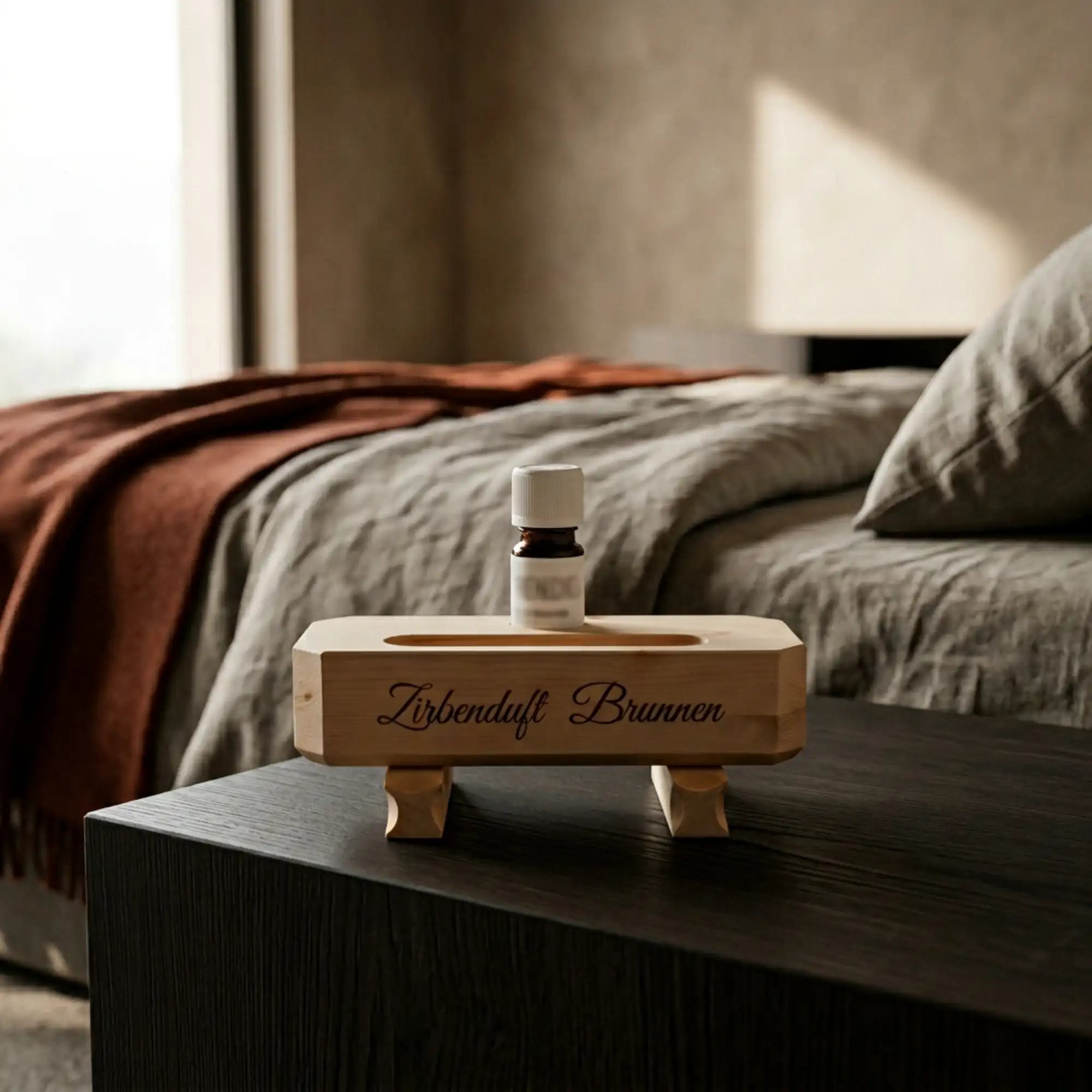 Zirbenduft-Brunnen auf dunklem Nachttisch in einem modernen Schlafzimmer mit Greige- und Terracotta-Textilien. Zirbenduft-Brunnen auf dunklem Nachttisch in einem modernen Schlafzimmer mit Greige- und Terracotta-Textilien.