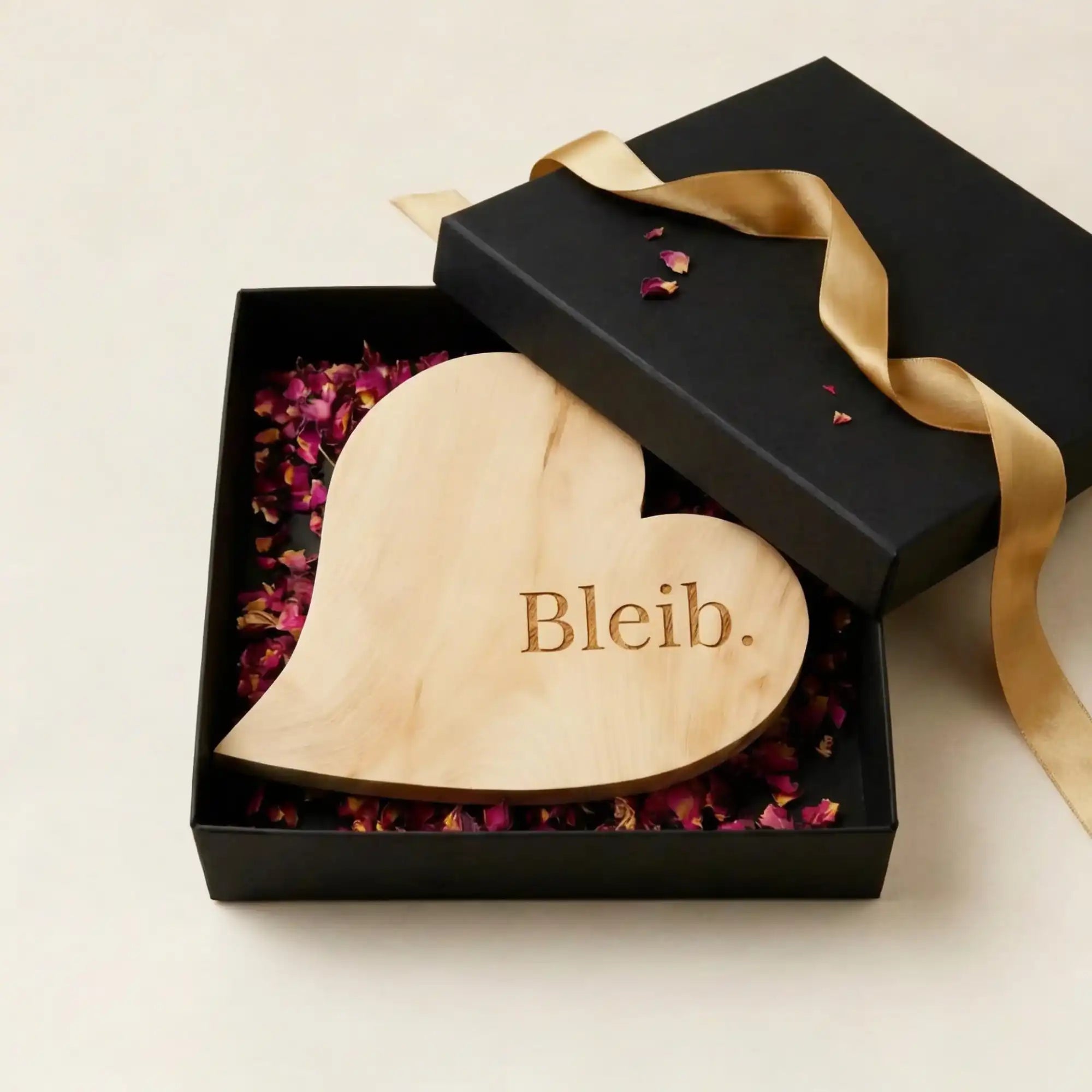 Muttertagsgeschenk Zirbenherz Bleib. in schwarzer geoeffneten Geschenkbox mit Rosbenblueten und goldener Satin Schleife. Muttertagsgeschenk Zirbenherz Bleib. in schwarzer geoeffneten Geschenkbox mit Rosbenblueten und goldener Satin Schleife.
