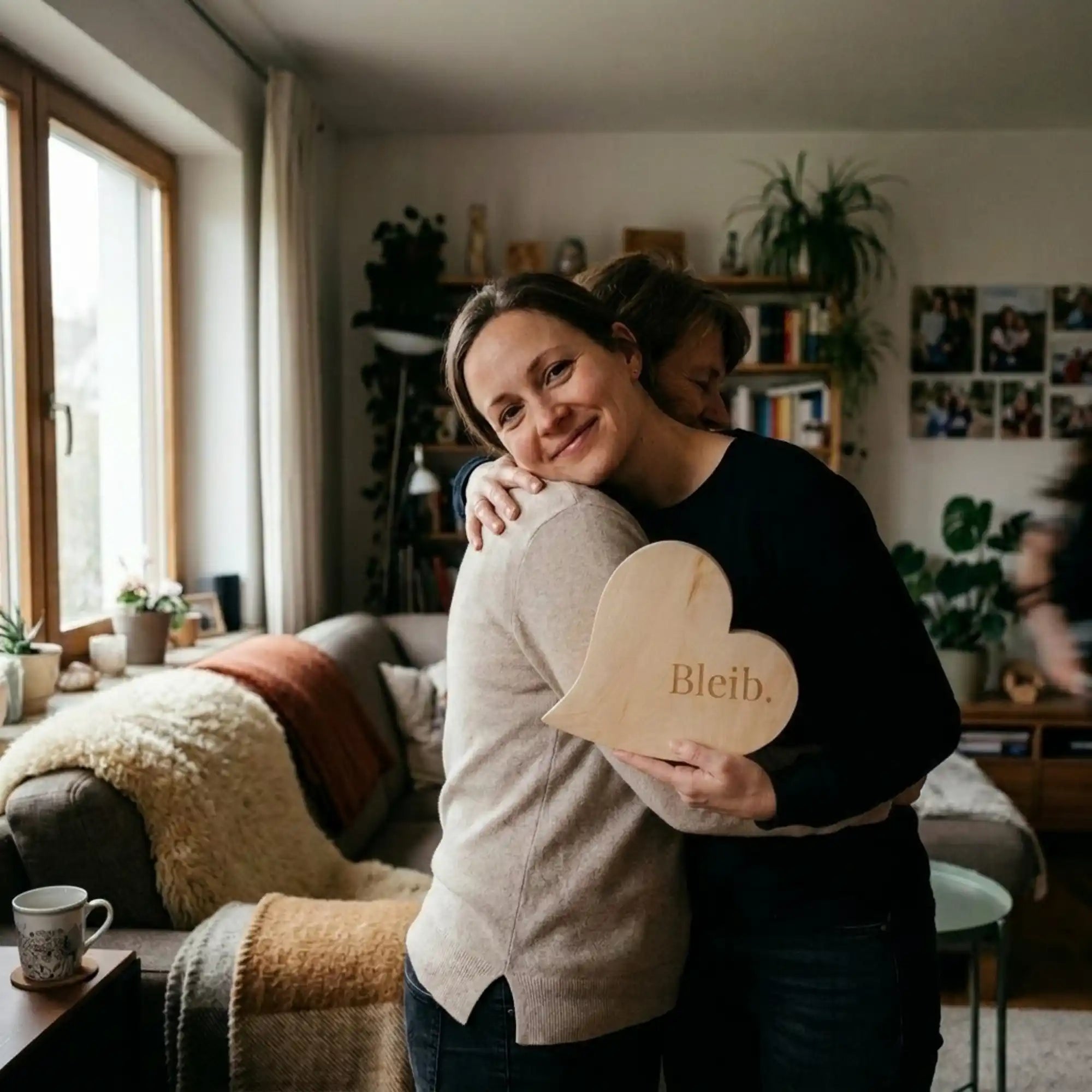 Zirbenherz mit Gravur „Bleib.“ als emotionales Muttertagsgeschenk – zwei Frauen umarmen sich herzlich in einem gemuetlichen Wohnzimmer. Zirbenherz mit Gravur „Bleib.“ als emotionales Muttertagsgeschenk – zwei Frauen umarmen sich herzlich in einem gemuetlichen Wohnzimmer.