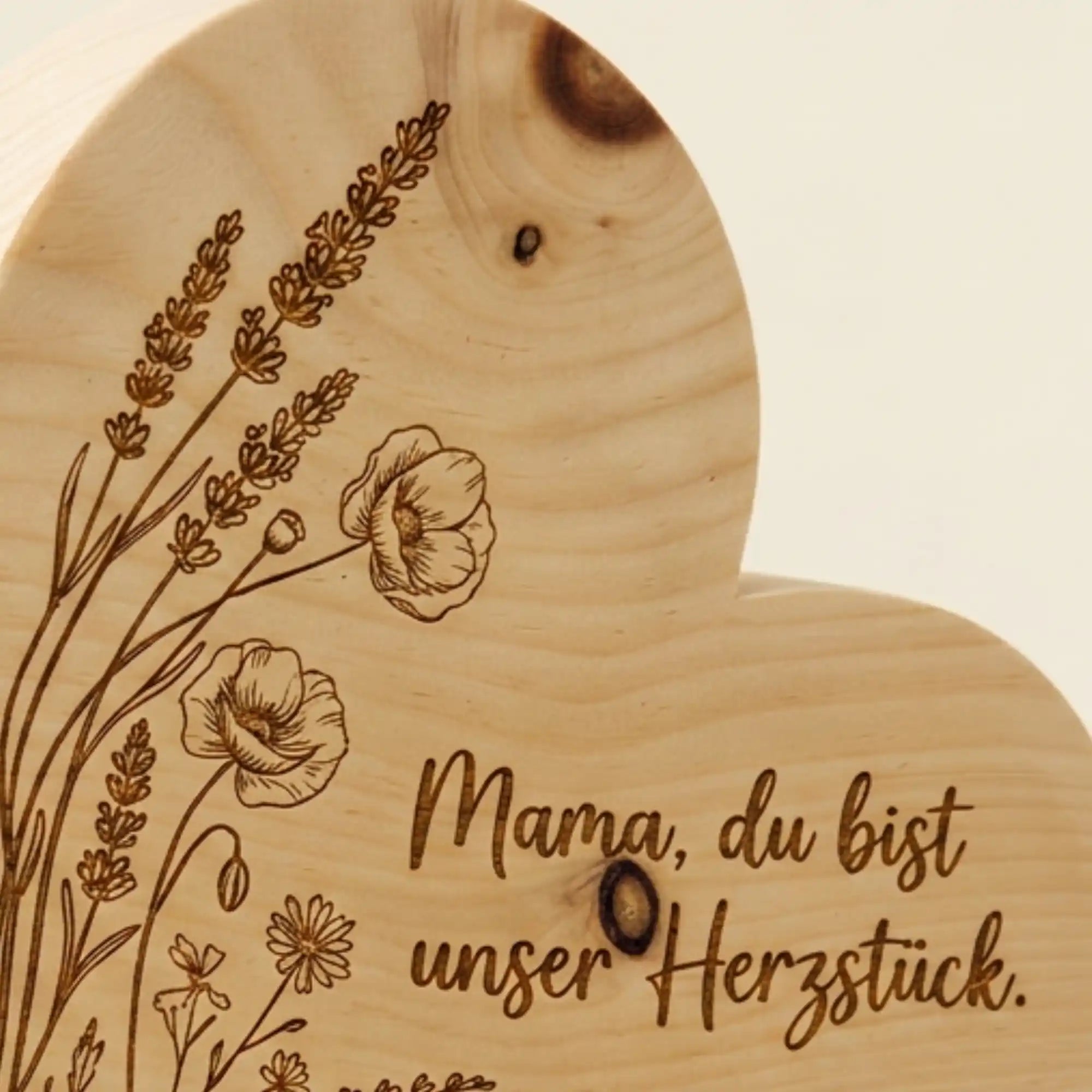 Nahaufnahme der praezisen Lasergravur Mama, du bist unser Herzstueck mit Wildblumen auf massivem Zirbenholz zum Muttertag 2026. Nahaufnahme der praezisen Lasergravur Mama, du bist unser Herzstueck mit Wildblumen auf massivem Zirbenholz zum Muttertag 2026.