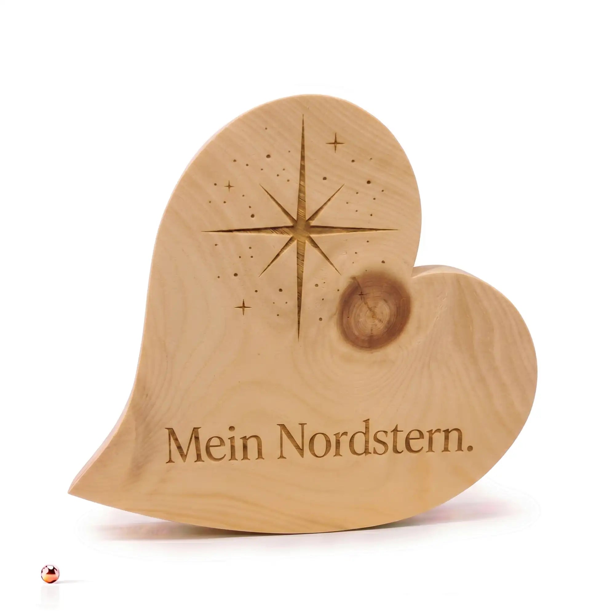 Zirbenherz Mein Nordstern aus Holz mit Gravur und Sternmotiv auf Holzoberflaeche mit unscharfem Hintergrund. Zirbenherz Mein Nordstern aus Holz mit Gravur und Sternmotiv auf Holzoberflaeche mit unscharfem Hintergrund.
