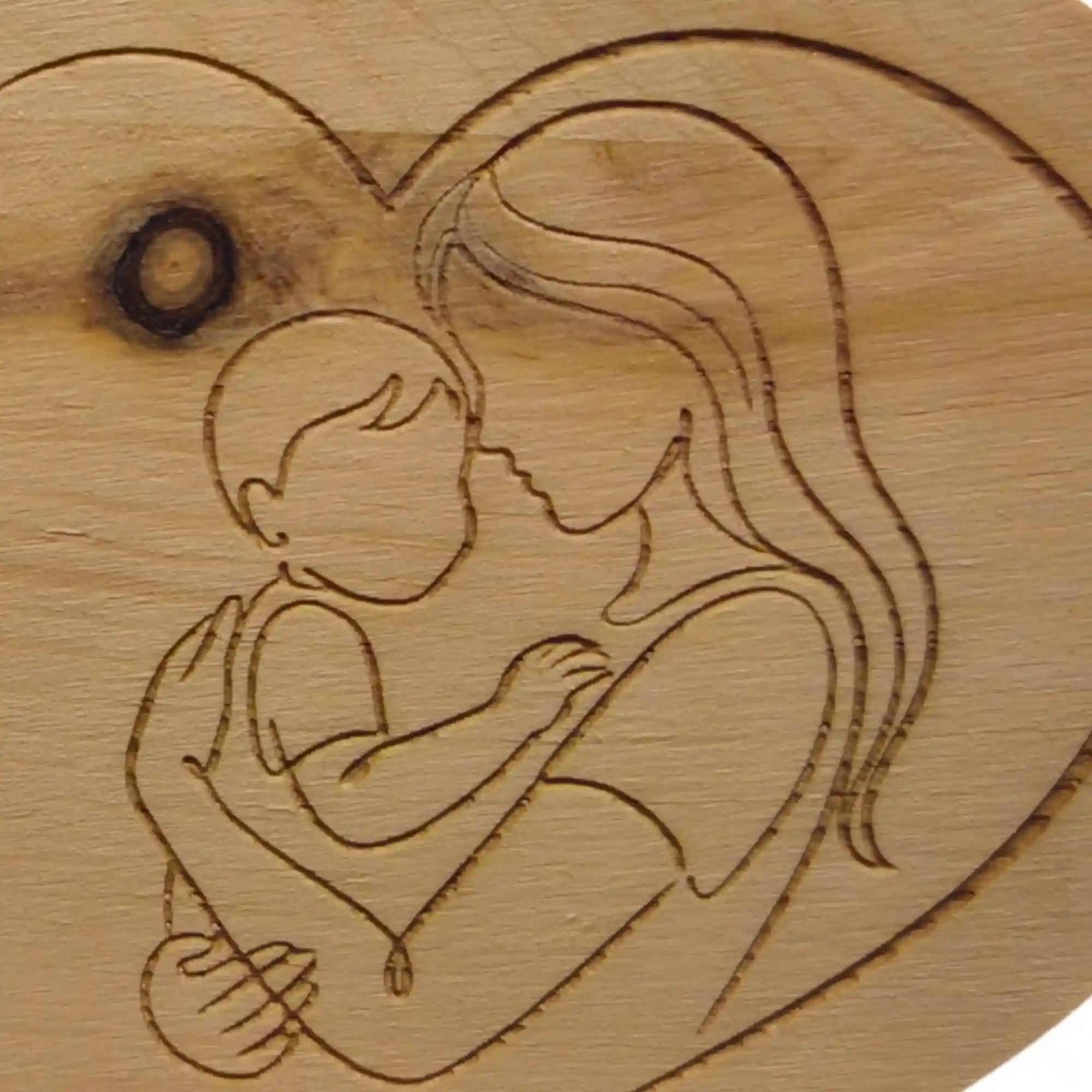 Detailaufnahme des Mutter Kind Motivs als Gravur auf Zirbenherz aus Holz mit sichtbarer Maserung.