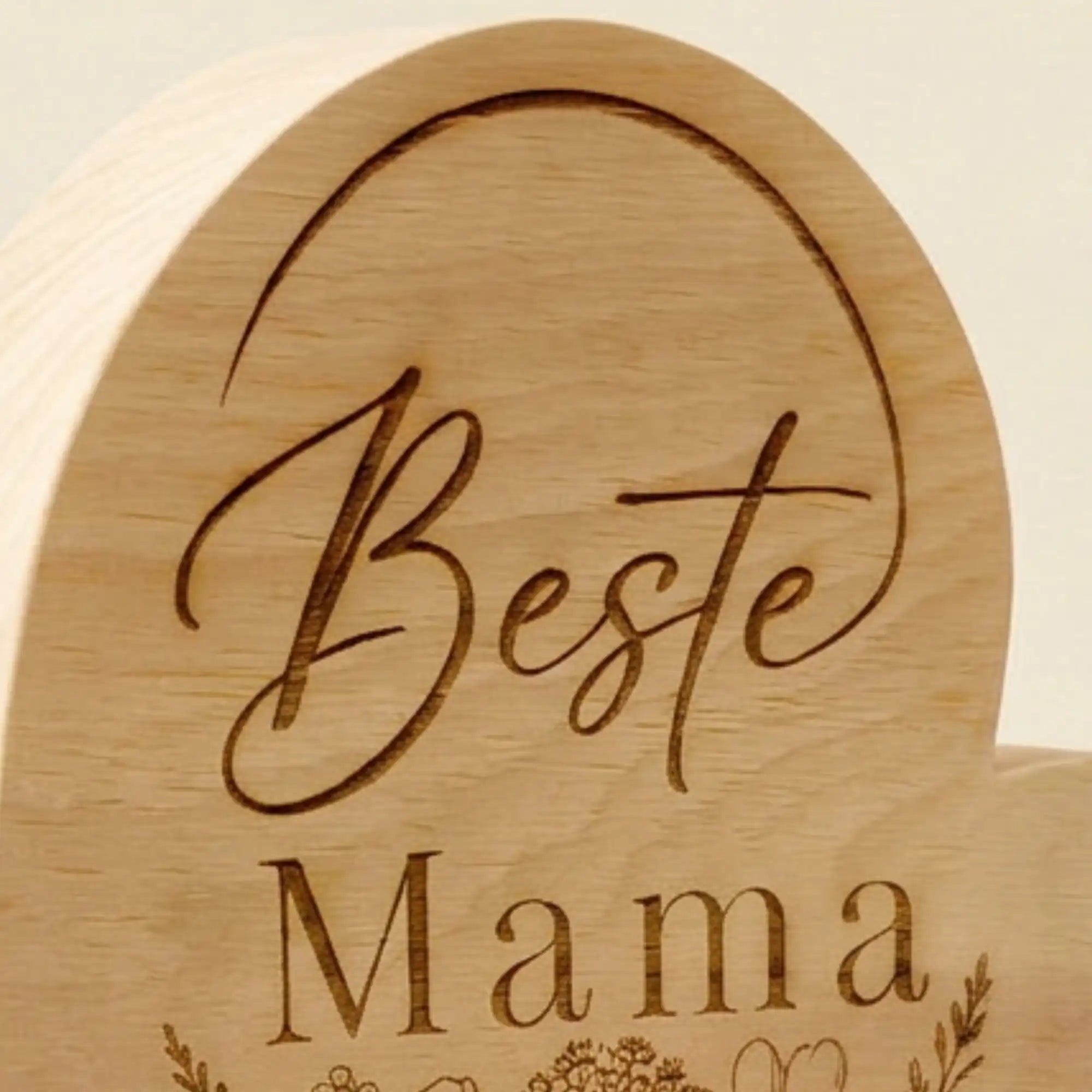 Nahaufnahme der Gravur Beste Mama mit feinem Blumenstrauss auf Zirbenholzherz als Geschenkidee zum Muttertag. Nahaufnahme der Gravur Beste Mama mit feinem Blumenstrauss auf Zirbenholzherz als Geschenkidee zum Muttertag.