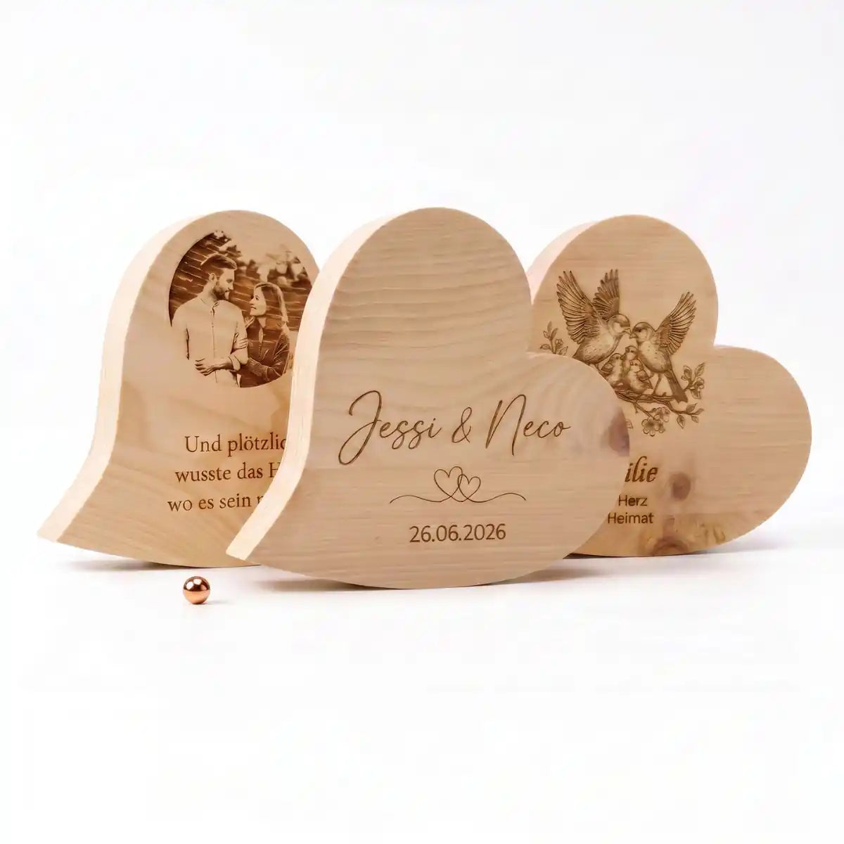 Kollektion aus drei massiven Zirbenherzen mit individueller Fotogravur Namensgravur Jessi und Neco sowie Familienvogelmotiv freigestellt auf weissem Hintergrund mit viel Platz unten fuer Text.