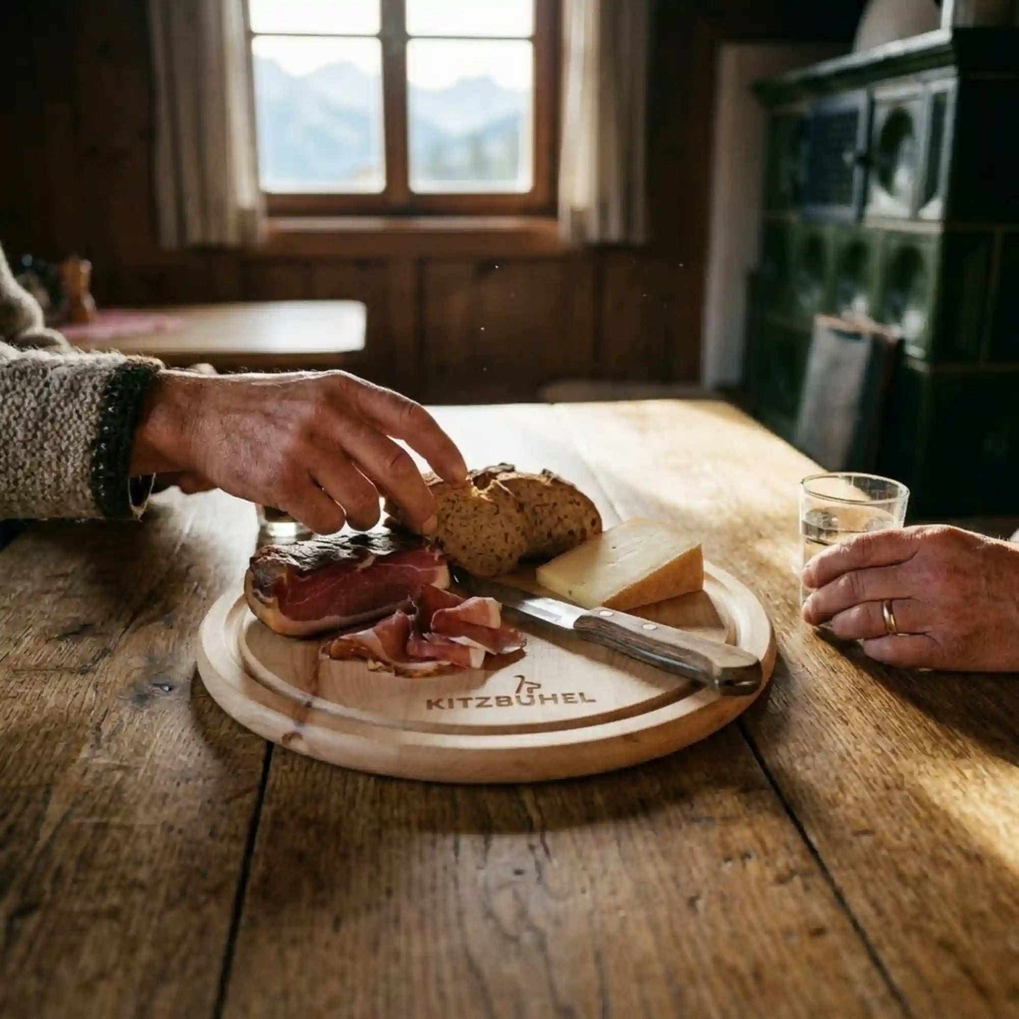 Rundes Zirbenholz-Jausenbrett mit Kitzbuehel Gravur und Brettljause auf rustikalem Eichentisch in einer Tiroler Berghuette. Rundes Zirbenholz-Jausenbrett mit Kitzbuehel Gravur und Brettljause auf rustikalem Eichentisch in einer Tiroler Berghuette.