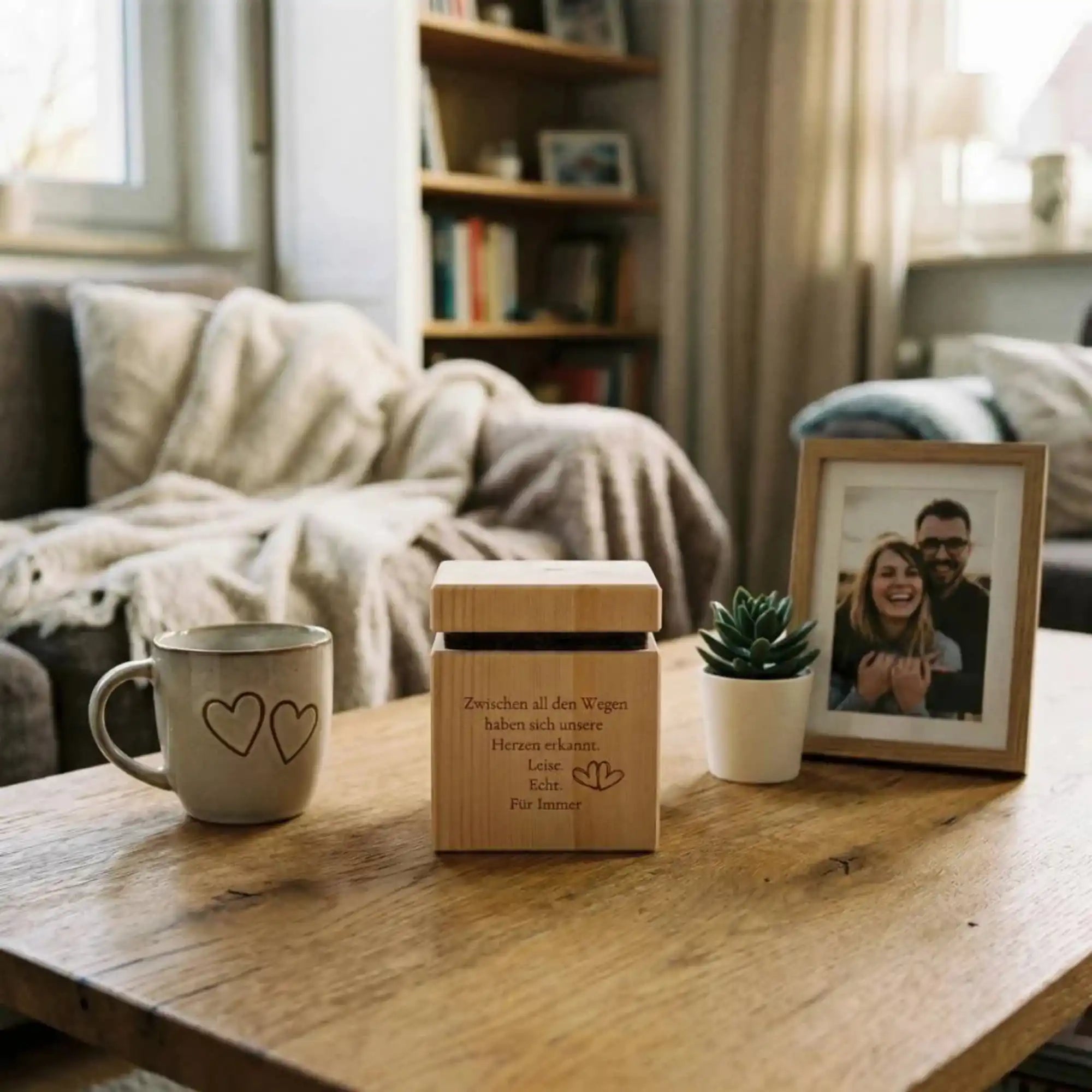 Zirbenwuerfel mit Gravur Modell HerzZeit neben Paarfoto auf Couchtisch als Geschenk durch Lasergravur aus Zirbenholz. Zirbenwuerfel mit Gravur Modell HerzZeit neben Paarfoto auf Couchtisch als Geschenk durch Lasergravur aus Zirbenholz.