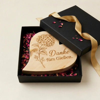 Graviertes Zirbenholzherz "Danke fuers Gießen" in einer edlen schwarzen Geschenkbox mit Rosenblueten.