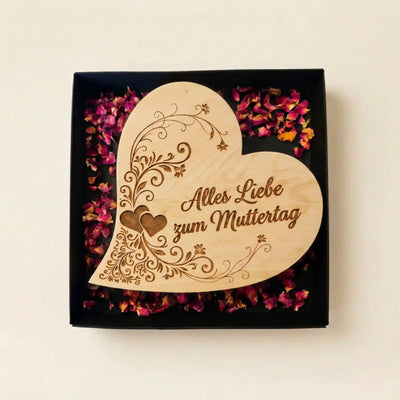 Geoeffnetes Geschenke-Set mit dem Zirbenherz „Alles Liebe zum Muttertag“, praesentiert in einer edlen Box auf echten Rosenblueten.