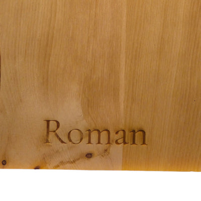 Detailansicht einer eingebrannten personalisierten Lasergravur mit Wunschname Roman auf einem rustikalen Brotzeitbrett aus Zirbe.
