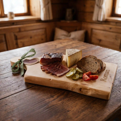 XL Brotzeitbrett aus Zirbenholz reich belegt mit Speck Kaese Tomaten und Gurken sowie Lasergravur Roman auf urigem Altholztisch in einer Berghuette.