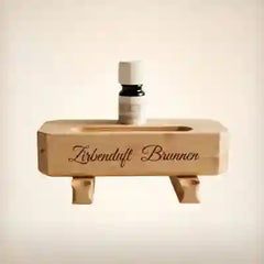 Zirbenduft Brunnen aus massivem Holz mit Zirbenoel Flasche als rundes Bubble Navigationsbild fuer die Kategorie Zirbenprodukte.
