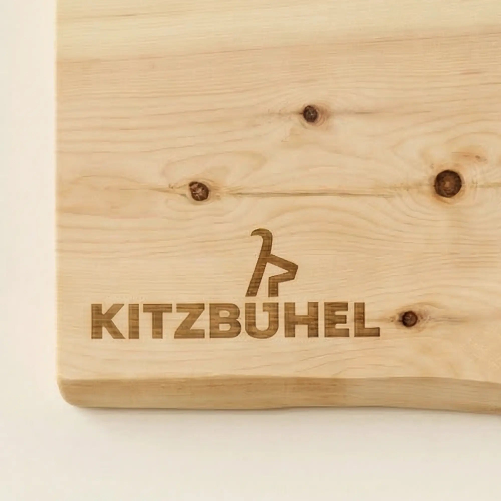 Detailansicht der lasergravierten Kitzbuehel-Schriftzug-Gravur auf einem Jausenbrett aus hellem Zirbenholz.
