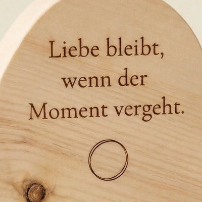 Nahaufnahme der Gravur Liebe bleibt auf einem Zirbenherz mit Infinity-Symbol. Detailansicht der Geschenkidee fuer Paare zur Hochzeit.