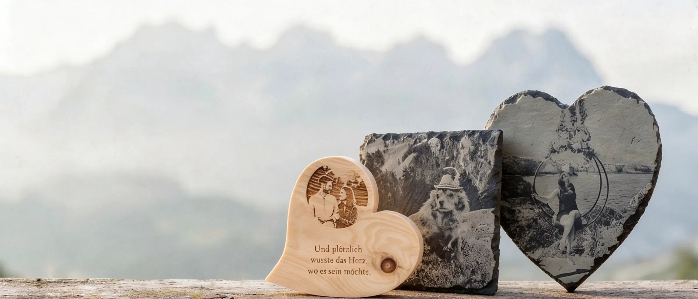 Personalisiertes Zirbenherz und Schieferherz mit Fotogravur von Menschen und Hund vor dem Bergmassiv Wilder Kaiser.