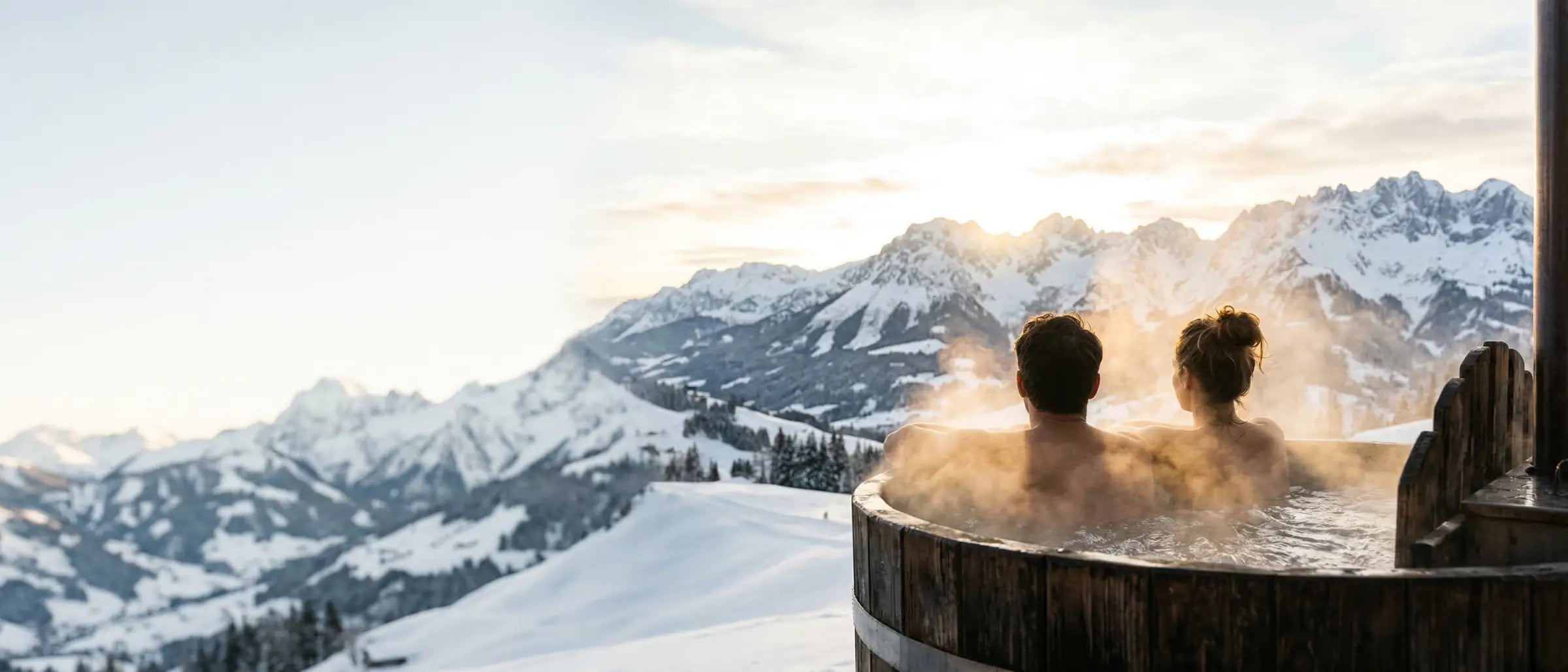 Paar genießt Sonnenaufgang im rustikalen Hotpot über Kitzbuehel. Inspiration für Selfcare und Geschenke von GeschenkeReich.