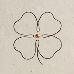Fein gezeichnetes vierblaettriges Kleeblatt als minimalistische Liniengrafik auf hellem, strukturiertem Papier.