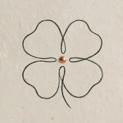 Fein gezeichnetes vierblaettriges Kleeblatt als minimalistische Liniengrafik auf hellem, strukturiertem Papier.
