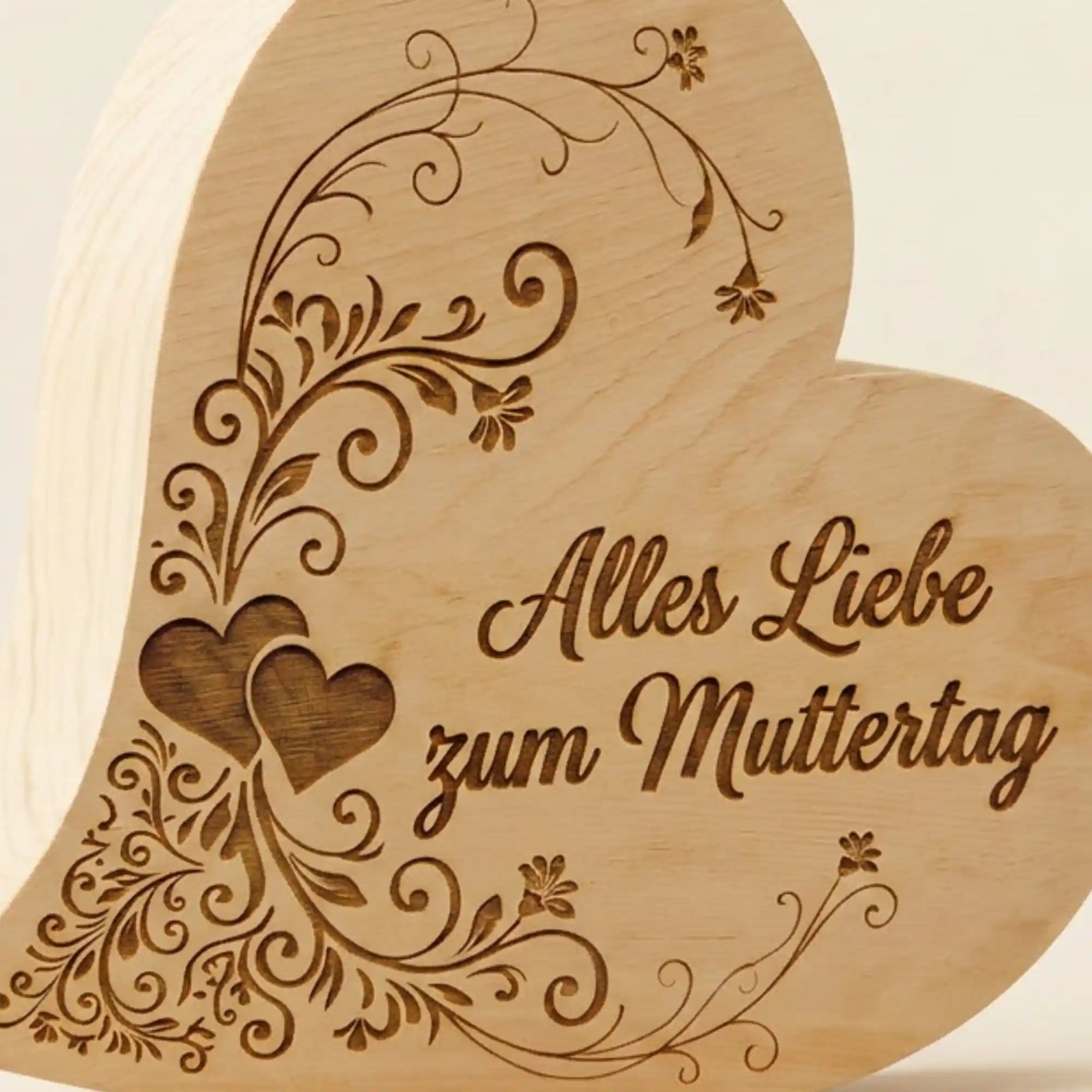 Detailansicht der tiefen Gravur „Alles Liebe zum Muttertag“ mit Herzverzierung auf einem massiven Zirbenherz.