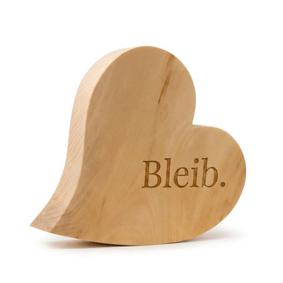 Zirbenherz als emotionales Muttertagsgeschenk mit Gravur „Bleib.“ aus massivem Zirbenholz auf weissem Hintergrund.