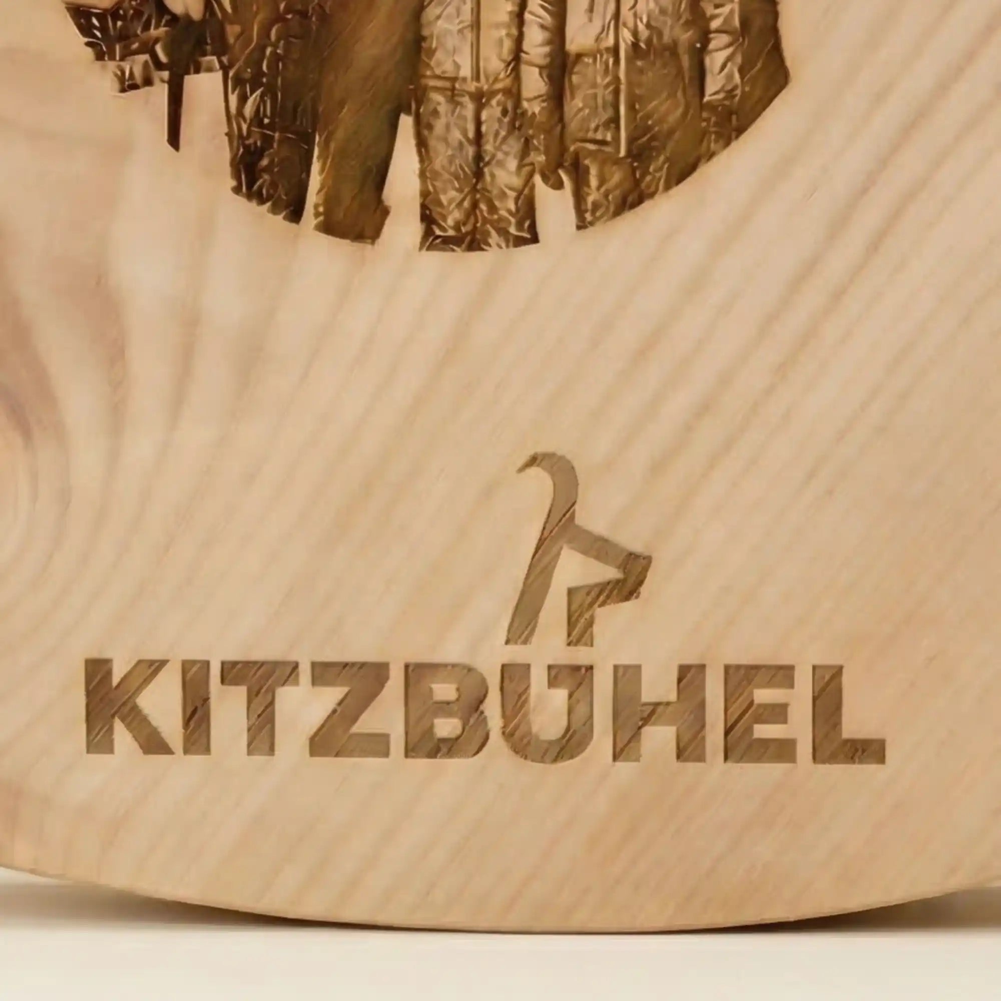Detailansicht der praezisen Lasergravur: Ikonischer Kitzbuehel Schriftzug und Gams Logo auf massivem Alpen-Zirbenholz. 