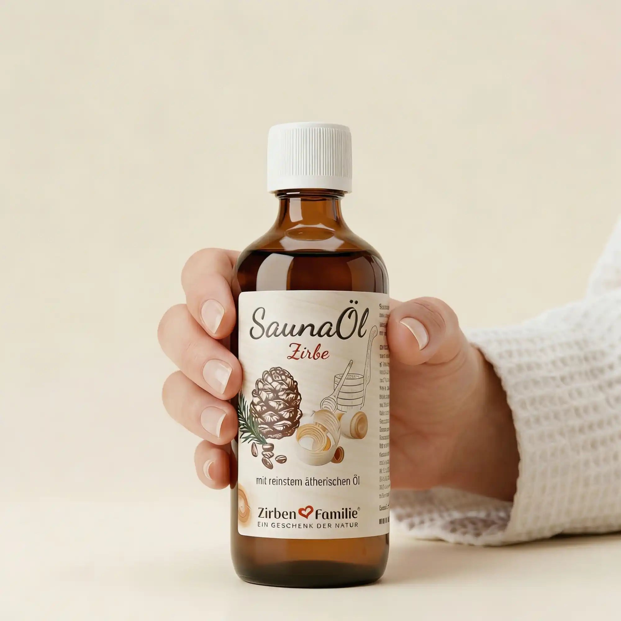 Hand haelt eine 100ml Saunaoel Flasche im Spa-Ambiente vor hellem strukturiertem Hintergrund.