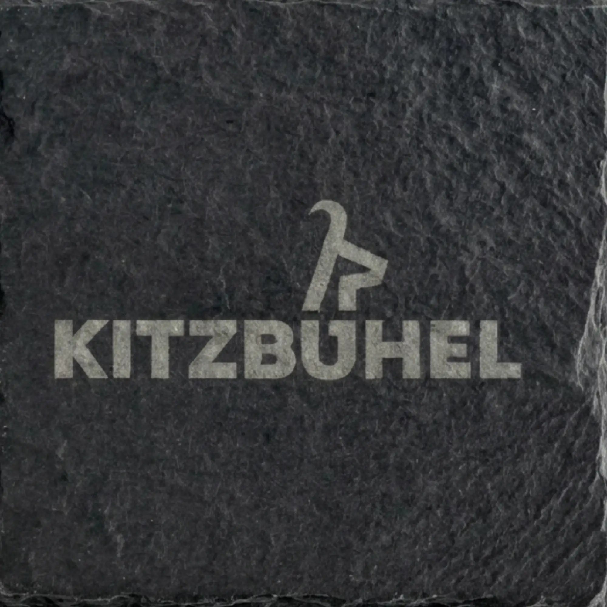Nahaufnahme eines Schiefer Untersetzers mit grosser, lizenzierter Kitzbuehel Schriftzug Gravur auf dunklem Naturstein.