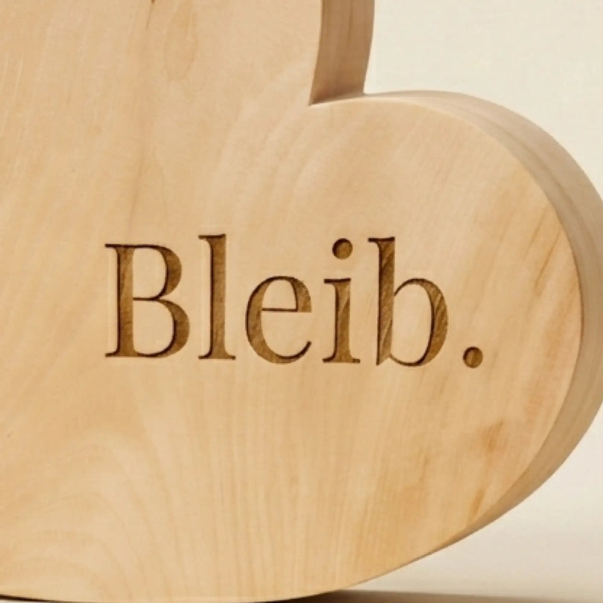 Nahaufnahme der präzisen Lasergravur Bleib auf echtem Zirbenholz aus regionaler Handarbeit.
