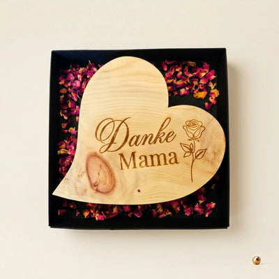Zirbenherz Danke Mama mit Rosengravur als Muttertagsgeschenk aus echtem Zirbenholz in schwarzer Geschenkebox auf Bluetenbett.