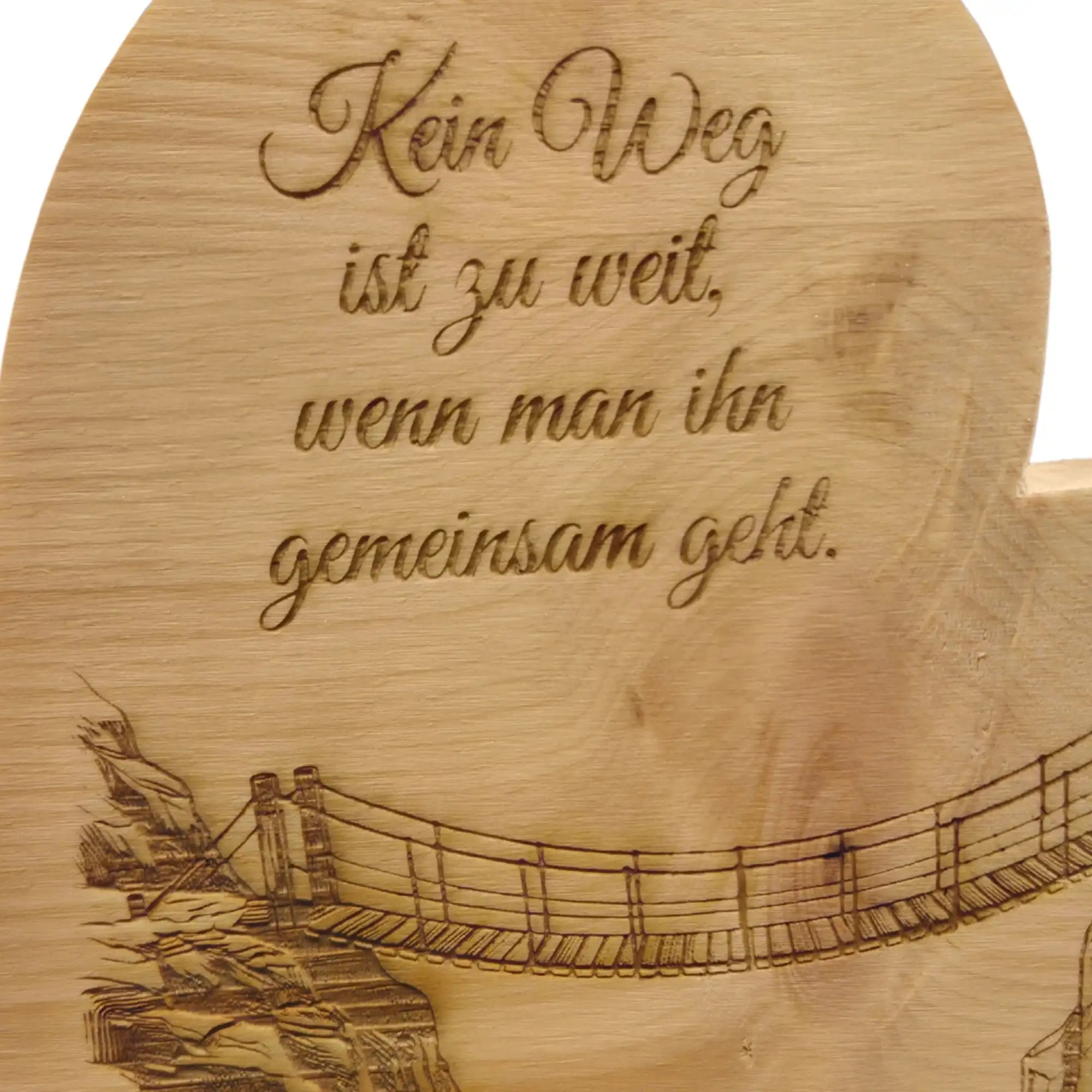 Detailaufnahme der Gravur mit Haengebruecke zwischen zwei Felsen auf Zirbenherz aus Holz mit sichtbarer Maserung.