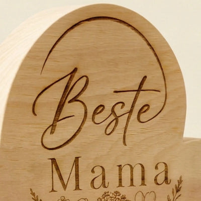 Nahaufnahme der Gravur Beste Mama mit feinem Blumenstrauss auf Zirbenholzherz als Geschenkidee zum Muttertag.