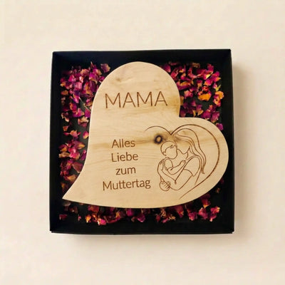 Geoeffnete Geschenkbox zum Muttertag 2026 mit Zirbenherz Mutterliebe inklusive Mutter-Kind-Zeichnung auf Rosenblueten.