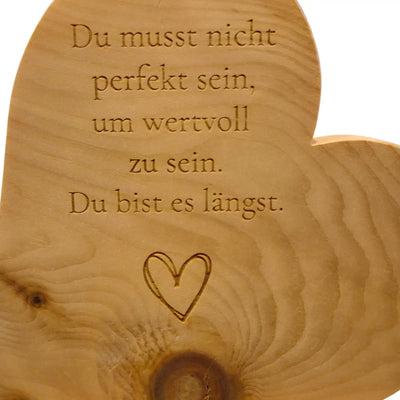 Detailaufnahme einer Lasergravur mit dem Spruch "Du bist es laengst" auf einem Zirbenherz aus Holz mit sichtbarer Maserung.