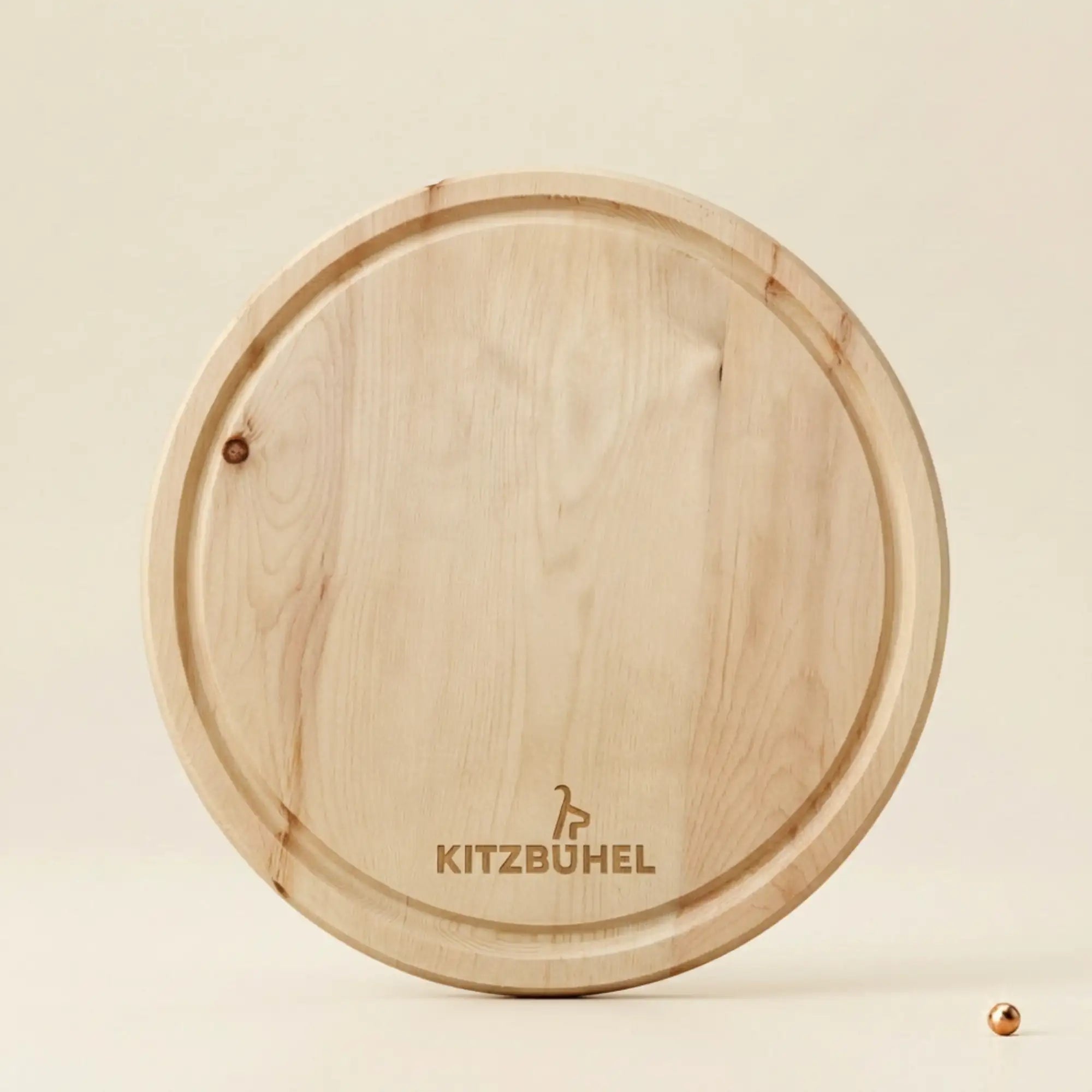 Rundes Jausenbrett aus massivem Tiroler Zirbenholz mit offizieller Kitzbuehel Lizenzgravur, Durchmesser 25 cm, auf neutralem Hintergrund.