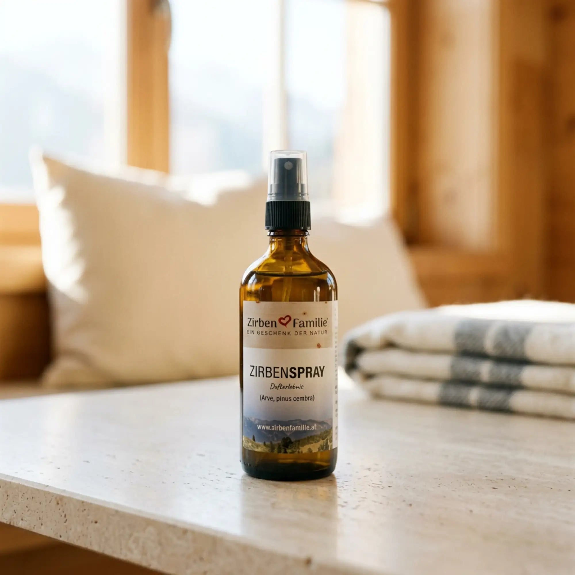 100ml Zirbenspray Glasflasche in einem hellen, modernen alpinen Ambiente neben Leinentextilien.
