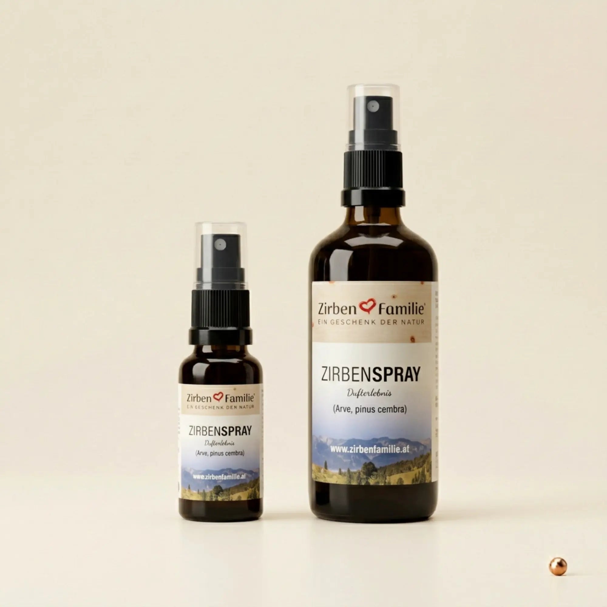Zirbenspray 20ml und 100ml Glasflaschen im Vergleich, stehend und zentriert auf hellem Papier mit Kupferpunkt-Akzent.