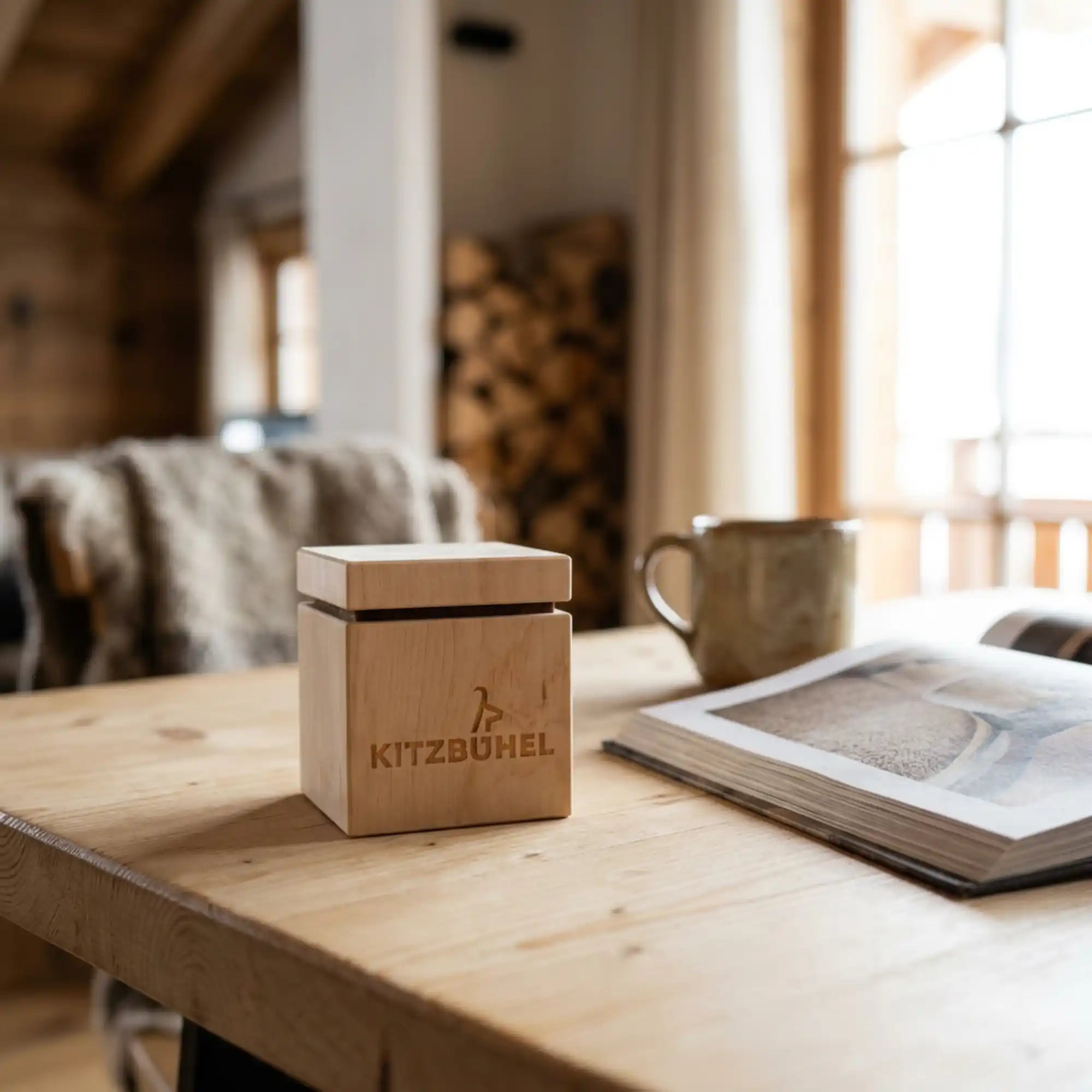 Zirbenwuerfel mit lizenziertem Kitzbuehel Schriftzug auf hellem Fichtenholz Esstisch im Chalet.
