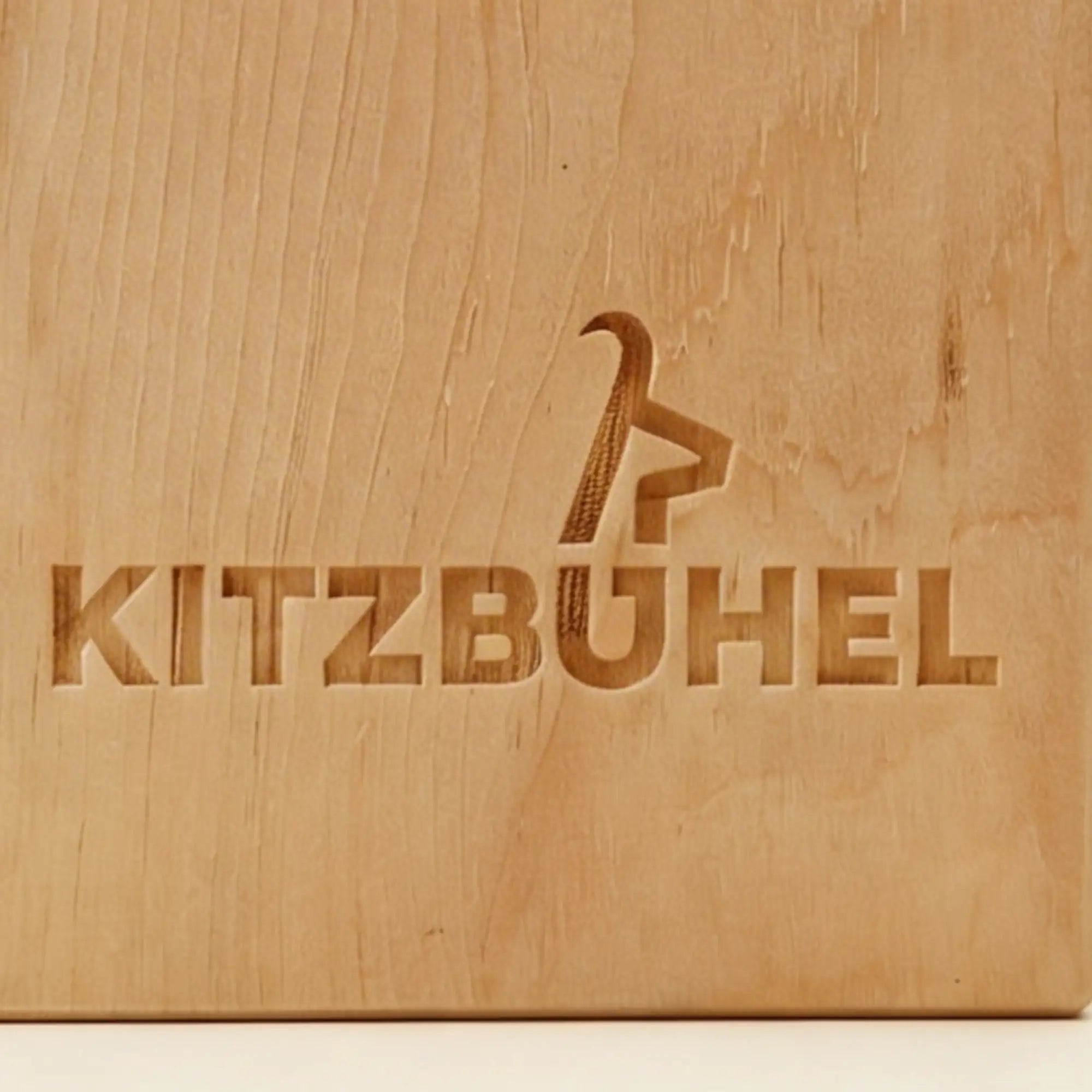 Nahaufnahme der praezisen Kitzbuehel Schriftzug Gravur im Zirbenholz.