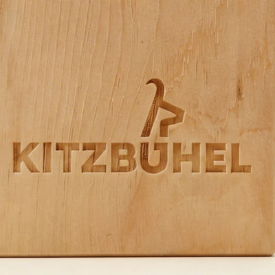 Nahaufnahme der praezisen Kitzbuehel Schriftzug Gravur im Zirbenholz.